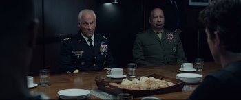 Movie still from “Fantastic Four” (2015), directed by Josh Trank – Two men in uniform sitting at a table with food; Medium shot, Over the shoulder angle