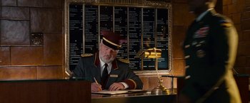 Movie still from “Fantastic Four: Rise of the Silver Surfer” (2007), directed by Tim Story – A man sitting at a table writing on a piece of paper; Medium shot, Low angle