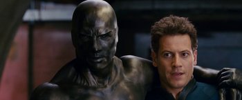 Movie still from “Fantastic Four: Rise of the Silver Surfer” (2007), directed by Tim Story – A man standing next to a statue of a man with no shirt on; Close Up shot, High angle