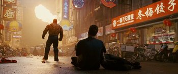 Movie still from “Fantastic Four: Rise of the Silver Surfer” (2007), directed by Tim Story – A man sitting on the ground on the street; Wide shot, Over the shoulder angle