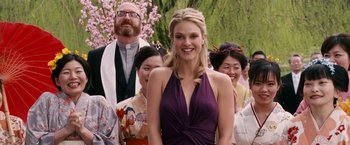 Movie still from “Fantastic Four: Rise of the Silver Surfer” (2007), directed by Tim Story – A woman in a purple dress standing in front of a group of people; Close Up shot, Over the shoulder angle