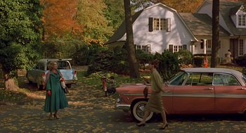 Movie still from “Far from Heaven” (2002), directed by Todd Haynes – A woman walking past an old car in a driveway; Extreme Wide shot, High angle