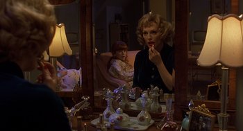 Movie still from “Far from Heaven” (2002), directed by Todd Haynes – A woman sitting in front of a mirror putting lipstick on her lips; Medium shot, Over the shoulder angle