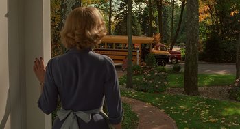 Movie still from “Far from Heaven” (2002), directed by Todd Haynes – A woman walking down a path in front of a school bus; Wide shot, Over the shoulder angle
