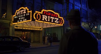 Movie still from “Far from Heaven” (2002), directed by Todd Haynes – A man walking on the sidewalk in front of a theater; Extreme Wide shot, High angle