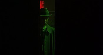 Movie still from “Far from Heaven” (2002), directed by Todd Haynes – A man wearing a hat standing in a dark room; Medium shot, Over the shoulder angle