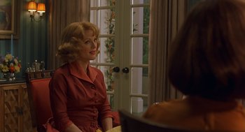 Movie still from “Far from Heaven” (2002), directed by Todd Haynes – A woman in a red dress sitting in front of a window; Medium shot, Over the shoulder angle