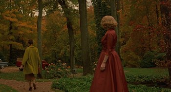 Movie still from “Far from Heaven” (2002), directed by Todd Haynes – A woman in a red dress standing in the woods; Wide shot, High angle