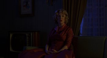Movie still from “Far from Heaven” (2002), directed by Todd Haynes – A woman in a red dress sitting on a couch; Medium shot, Over the shoulder angle