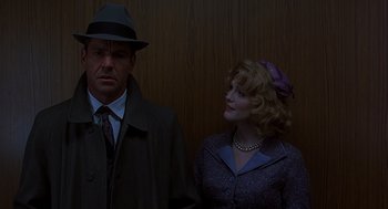Movie still from “Far from Heaven” (2002), directed by Todd Haynes – A man and a woman standing next to each other in front of a wooden wall; Medium shot, Over the shoulder angle
