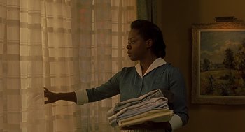 Movie still from “Far from Heaven” (2002), directed by Todd Haynes – A woman holding a stack of folded clothes; Medium shot, Low angle