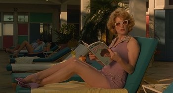 Movie still from “Far from Heaven” (2002), directed by Todd Haynes – A woman sitting on a chair reading a book; Medium shot, Low angle