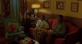 Movie still from “Far from Heaven” (2002), directed by Todd Haynes – A man and a woman sitting on a red couch; Medium shot, High angle