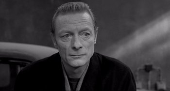 Movie still from “Faraway, So Close!” (1993), directed by Wim Wenders – Black and white photograph of a man in a black shirt; Close Up shot, High angle