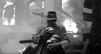 Movie still from “Faraway, So Close!” (1993), directed by Wim Wenders – An old man holding a camera in front of a fire place; Medium shot, Low angle