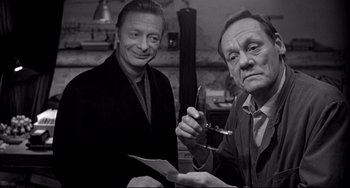 Movie still from “Faraway, So Close!” (1993), directed by Wim Wenders – A man holding a pair of scissors next to another man; Close Up shot, Over the shoulder angle