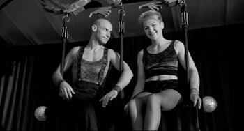 Movie still from “Faraway, So Close!” (1993), directed by Wim Wenders – A man and a woman sitting on a swing; Medium shot, Low angle