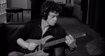 Movie still from “Faraway, So Close!” (1993), directed by Wim Wenders – A black and white photo of a man playing a guitar; Medium shot, Low angle