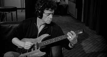 Movie still from “Faraway, So Close!” (1993), directed by Wim Wenders – A man wearing headphones and playing an electric guitar; Medium shot, Low angle