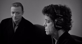 Movie still from “Faraway, So Close!” (1993), directed by Wim Wenders – A man wearing headphones and another man sitting in a chair; Close Up shot, Over the shoulder angle