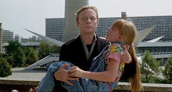 Movie still from “Faraway, So Close!” (1993), directed by Wim Wenders – An older man holding a young girl in his arms; Medium shot, Over the shoulder angle