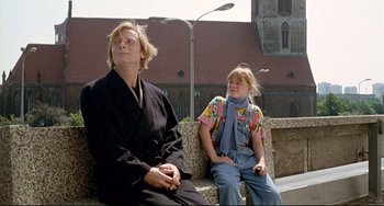 Movie still from “Faraway, So Close!” (1993), directed by Wim Wenders – A man and a little girl sitting on a park bench; Medium shot, Low angle