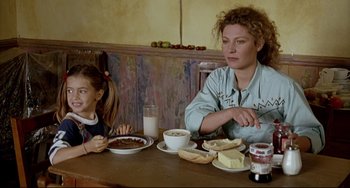 Movie still from “Faraway, So Close!” (1993), directed by Wim Wenders – A woman and a girl sitting at a table with plates of food; Medium shot, Over the shoulder angle