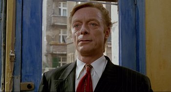 Movie still from “Faraway, So Close!” (1993), directed by Wim Wenders – A person wearing a suit and tie; Close Up shot, Low angle