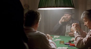 Movie still from “Faraway, So Close!” (1993), directed by Wim Wenders – Two men sitting at a green table drinking and playing cards; Medium shot, Over the shoulder angle