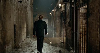 Movie still from “Faraway, So Close!” (1993), directed by Wim Wenders – A man in a suit walking down a dark alley way; Wide shot, High angle