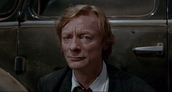 Movie still from “Faraway, So Close!” (1993), directed by Wim Wenders – A person wearing a suit and tie; Close Up shot, High angle