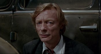 Movie still from “Faraway, So Close!” (1993), directed by Wim Wenders – A person wearing a suit and tie; Close Up shot, High angle