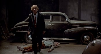Movie still from “Faraway, So Close!” (1993), directed by Wim Wenders – A man standing next to a dead body on the ground; Wide shot, Low angle