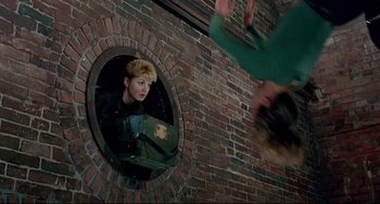 Movie still from “Faraway, So Close!” (1993), directed by Wim Wenders – A woman is looking into a round window; Wide shot, Overhead angle
