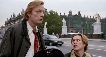 Movie still from “Faraway, So Close!” (1993), directed by Wim Wenders – Two people standing on a street near a building; Medium shot, Low angle