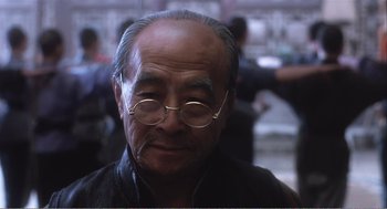 Movie still from “Farewell My Concubine” (1992), directed by Kaige Chen – An older man wearing glasses and a leather jacket; Close Up shot, Over the shoulder angle