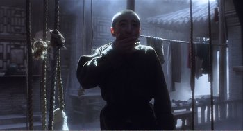 Movie still from “Farewell My Concubine” (1992), directed by Kaige Chen – A man with a shaved head standing in front of a building; Medium shot, Low angle
