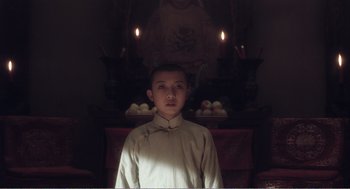 Movie still from “Farewell My Concubine” (1992), directed by Kaige Chen – A young man in a white shirt is standing in front of candles; Medium shot, Low angle