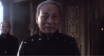 Movie still from “Farewell My Concubine” (1992), directed by Kaige Chen – An older man wearing a black shirt with gold rivets on it; Close Up shot, Low angle