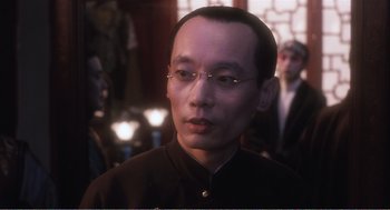 Movie still from “Farewell My Concubine” (1992), directed by Kaige Chen – A man with glasses is looking at the camera; Close Up shot, Over the shoulder angle