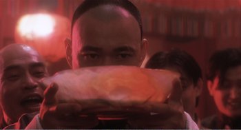 A man holding a piece of food in front of his face