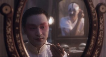 Movie still from “Farewell My Concubine” (1992), directed by Kaige Chen – A man with makeup on his face is holding a fork in front of a mirror; Close Up shot, Over the shoulder angle
