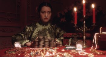 Movie still from “Farewell My Concubine” (1992), directed by Kaige Chen – A woman sitting at a table with a stack of cookies; Close Up shot, Over the shoulder angle