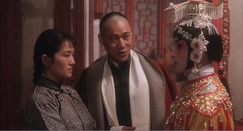 Movie still from “Farewell My Concubine” (1992), directed by Kaige Chen – A man and two women standing next to each other; Medium shot, Over the shoulder angle