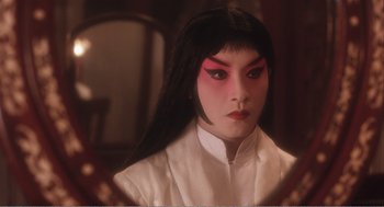 Movie still from “Farewell My Concubine” (1992), directed by Kaige Chen – A person with long black hair and red makeup; Close Up shot, Over the shoulder angle