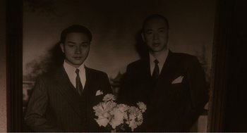 Movie still from “Farewell My Concubine” (1992), directed by Kaige Chen – A couple of men standing next to each other holding flowers; Medium shot, Low angle