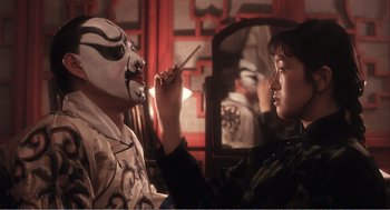 Movie still from “Farewell My Concubine” (1992), directed by Kaige Chen – A woman is painting a mask on a man's face in front of a mirror; Close Up shot, Over the shoulder angle