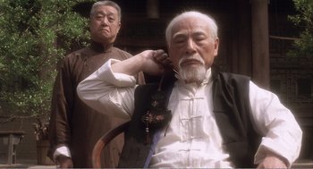 An older man is listening to music while another looks on