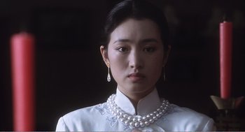 Movie still from “Farewell My Concubine” (1992), directed by Kaige Chen – A young woman wearing a white dress and a pearl necklace; Close Up shot, Over the shoulder angle