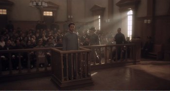 Movie still from “Farewell My Concubine” (1992), directed by Kaige Chen – A man standing in front of a crowd of people in a courtroom; Wide shot, High angle